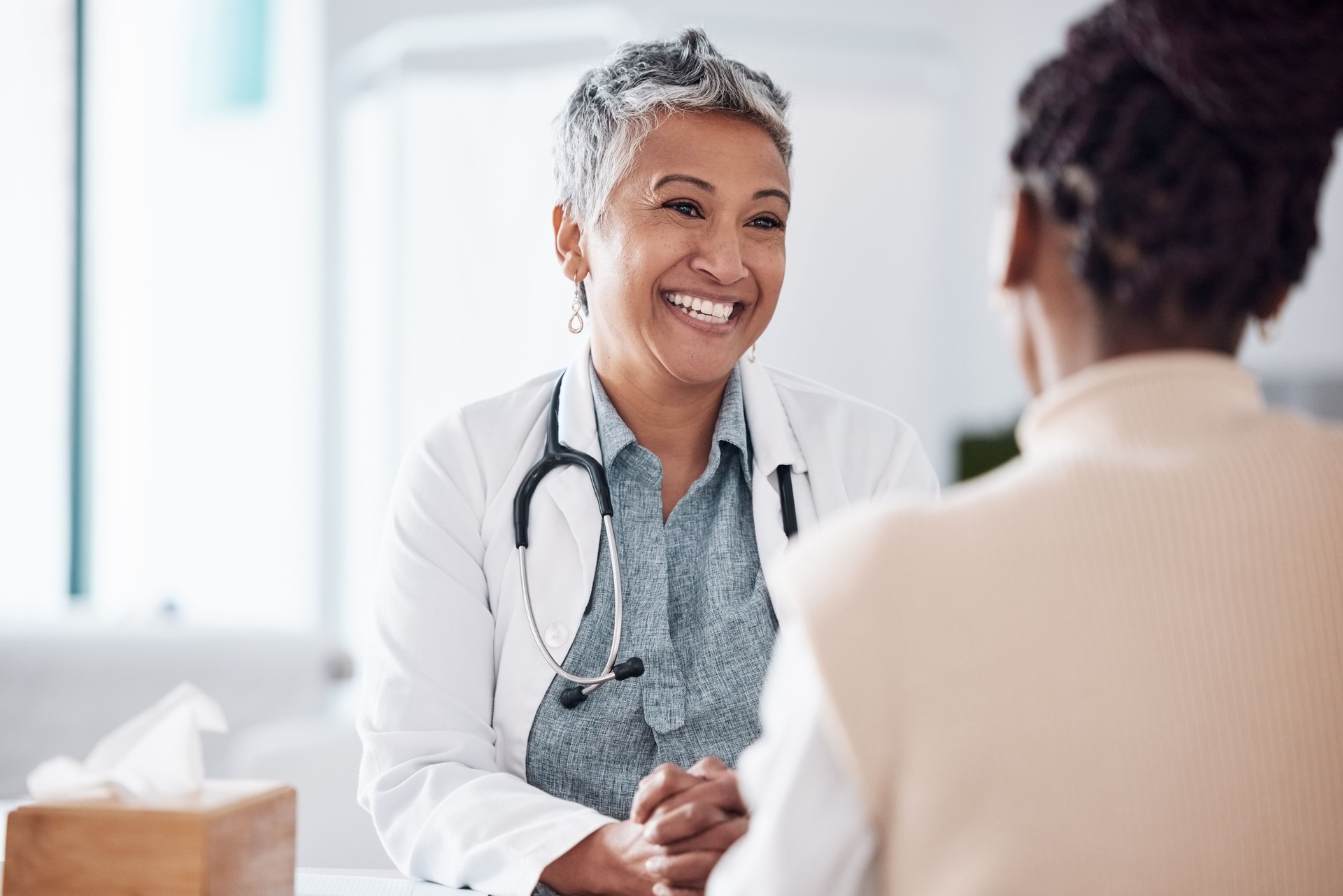 Happy, mature or doctor consulting a patient in meeting in hospital for healthcare help, feedback or support. People, medical or nurse with black woman talking or speaking of test results or advice
